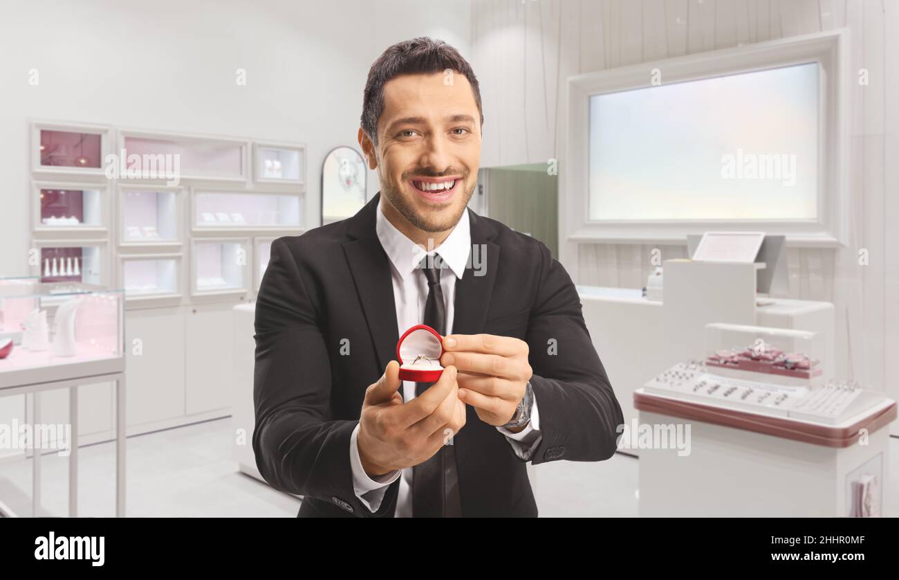 Jeune homme tenant une bague dans une boîte à l'intérieur d'une bijouterie Banque D'Images