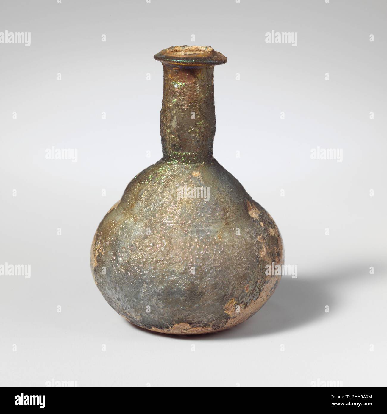 Flacon de parfum en verre 1st Century A.D. Roman translucide bleu pâle. Rebord replié, sur et à l'intérieur, avec rebord intérieur incliné vers le haut; col court, cylindrique, outilé autour de la base; épaule convexe, inclinée, avec repères d'outillage horizontaux en dessous; corps bombé, petit fond légèrement concave.Verre épais et épais.intact; piqûres et iridescences lourdes, avec des taches d'altération crémeuse.Flacon de parfum en verre 239648 Banque D'Images