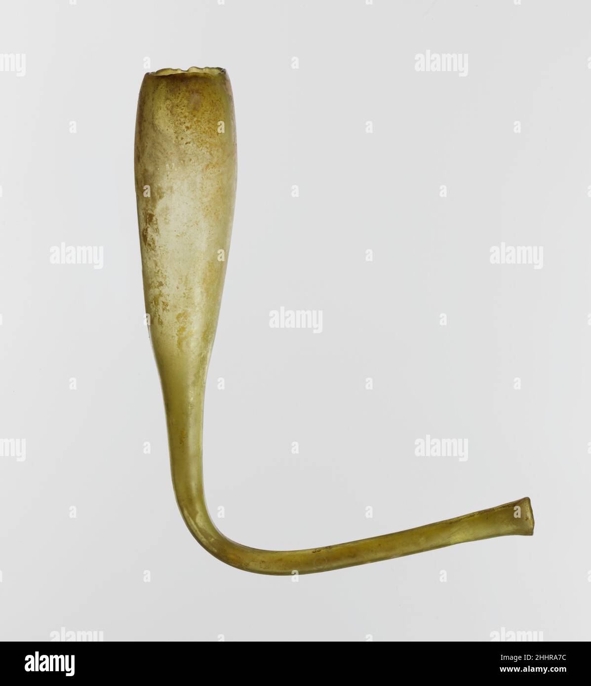 Navire en forme de corne de verre 4th–début du siècle 5th A.D. Roman translucide jaune clair vert.Rebord légèrement inversé, inégal et épaissi, arrondi dans la flamme; corps tubulaire allongé avec un côté légèrement convexe, tourné d'un côté à la base et continuant comme un tube long et mince; bec creux avec une bouche torchère et un bord arrondi et irrégulier à la fin.intact; quelques bulles allongées;taches de morcellement et d'intempéries irisées.Récipient en forme de corne en verre.Romain.4th–début 5th siècle A.D..Verre ; soufflé.Impérial tardif ou byzantin précoce.Verre Banque D'Images