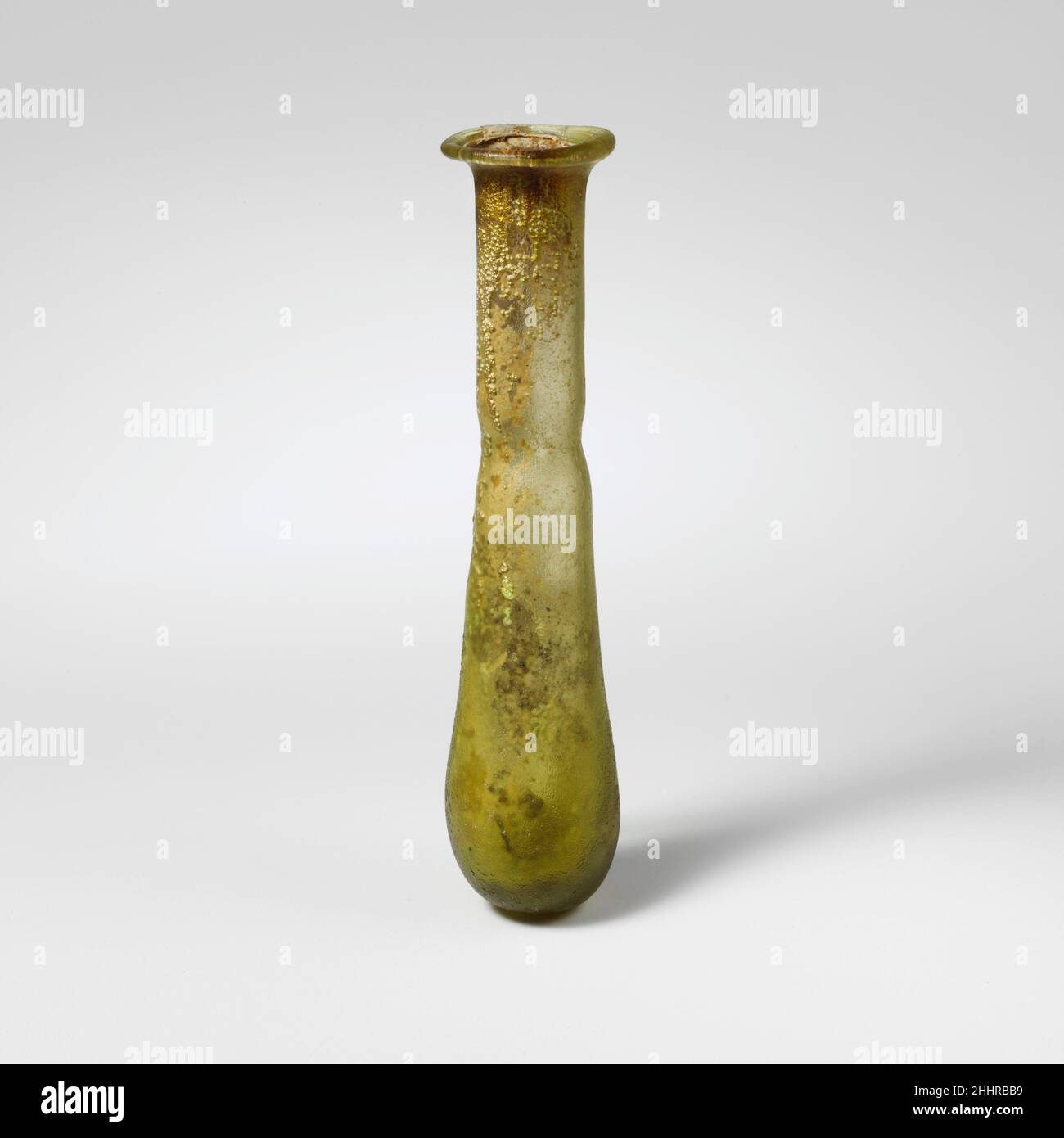 Flacon de parfum en verre mi-1st–début de 2nd siècle A.D. Roman jaune translucide vert.Rim plié, rond, et dans; col cylindrique, outillé autour de la base; corps mince, allongé piriforme; fond épais, aplati.intact; beaucoup de bulles; piqûres profondes, brillant irisé et morcellement.Flacon de parfum en verre 239796 Banque D'Images