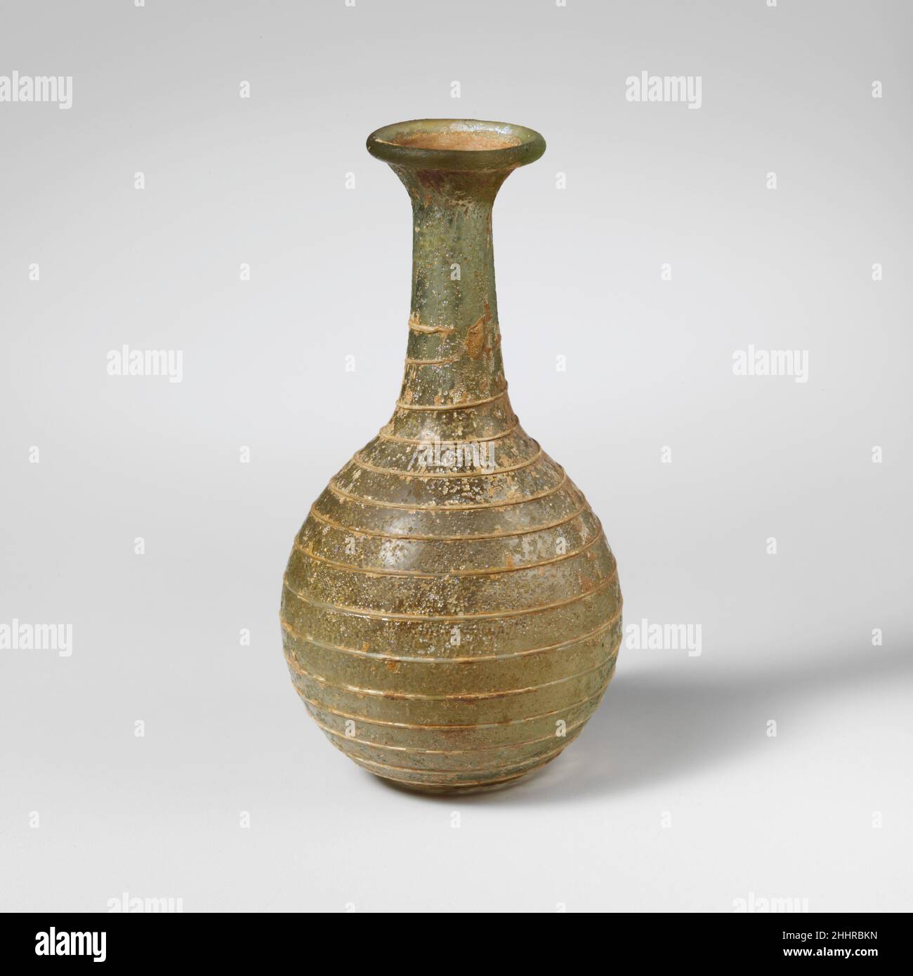 Flacon de parfum en verre 1st Century A.D. Roman bleu translucide vert, avec sentier de la même couleur. Rebord replié, rond et intérieur; col court et évasé;Col cylindrique, en expansion vers le bas; corps globulaire; fond légèrement aplati.un seul chemin appliqué sur le cou et dessiné vers le bas dans une spirale, se terminant sur le fond.intact; bulles de piqûre; piqûres et intempéries irisées.Flacon de parfum en verre 239798 Banque D'Images