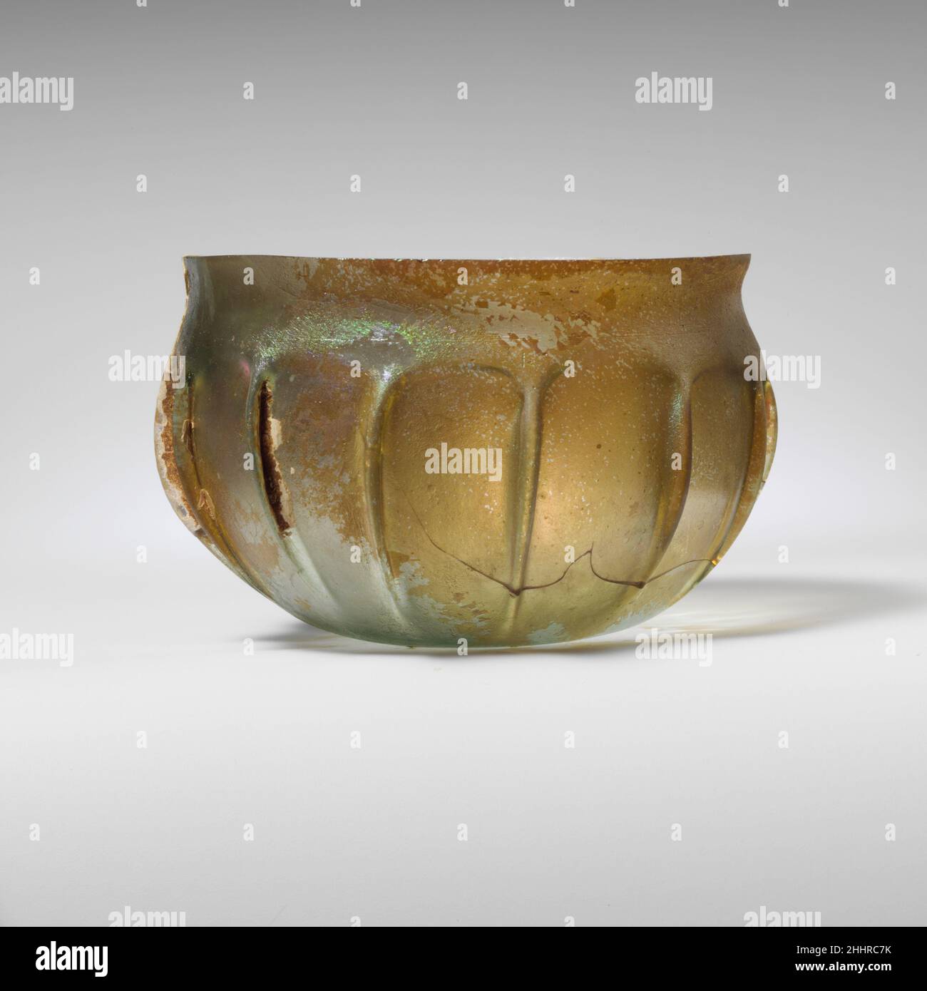 Bol en verre nervuré mi-1st Century A.D. Roman translucide bleu pâle vert.renfoncé, rebord inégal; col concave court; côté bombé courbé vers le fond plat.outil latéral en quatorze nervures verticales irrégulières.cassé avec des parties de rebord manquantes et un petit trou sur le côté; quelques bulles; morcellement, piqûres profondes et taches d'intempéries laiteuses épaisses.Bol en verre nervuré 239849 Banque D'Images