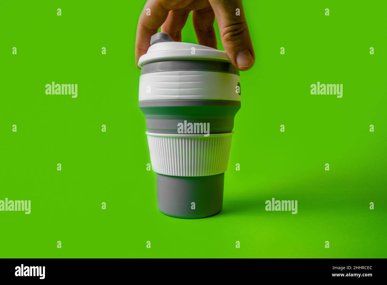 Tasse en silicone réutilisable pour café à la main sur fond vert. Banque D'Images