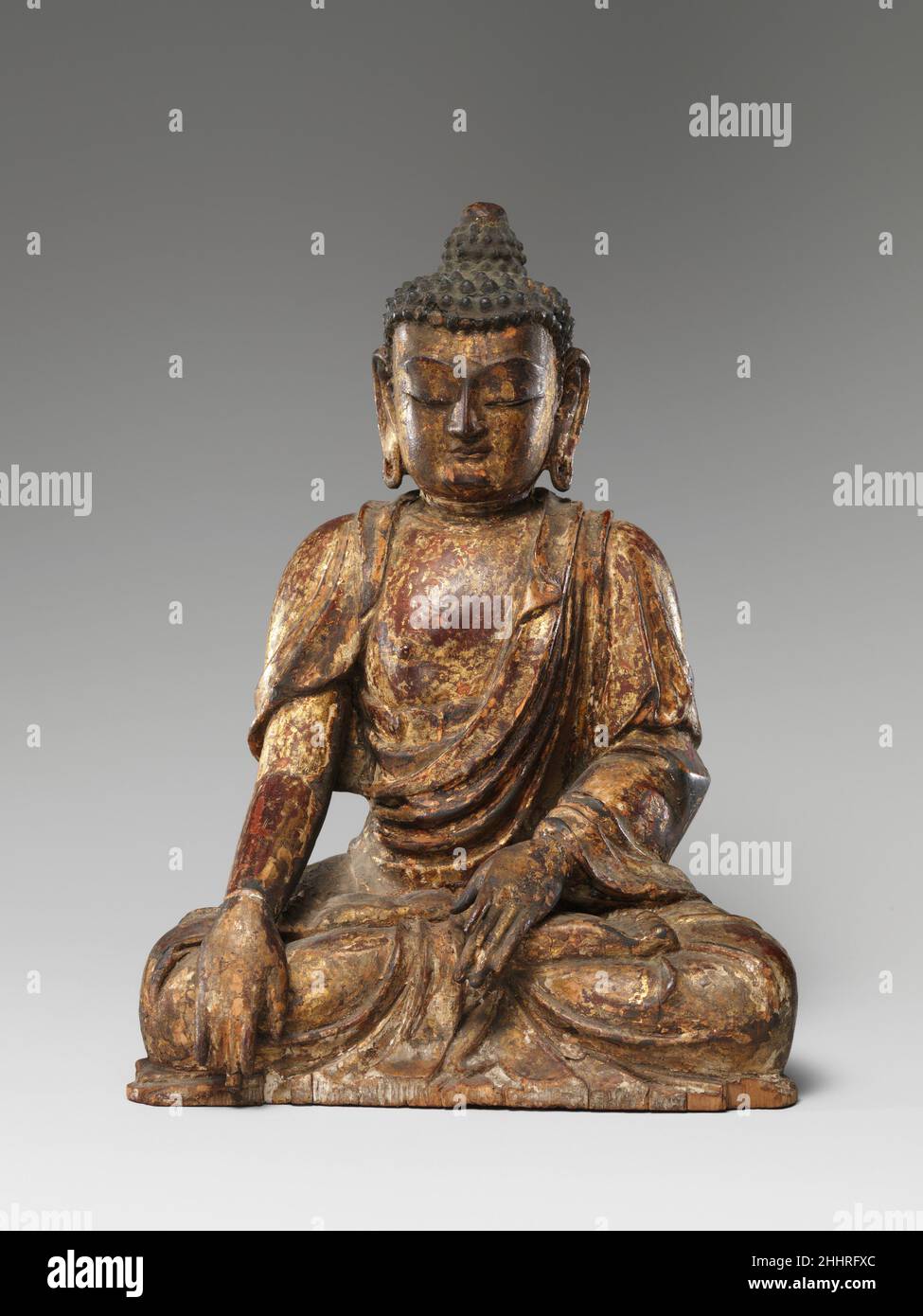 Bouddha assis daté de 1411 Chine le Bouddha est montré prêchant avec un doigt de sa main droite étendu pour appeler la terre à témoigner.Un panneau amovible à l'arrière révèle une cavité qui contenait un groupe de silks représentant les cinq organes vitaux, ainsi que des graines, des objets symboliques et des prières.L'une de ces prières comprend une date correspondant au 9 mai 1411, date à laquelle la sculpture a été dédiée.Bouddha assis 61686 Banque D'Images