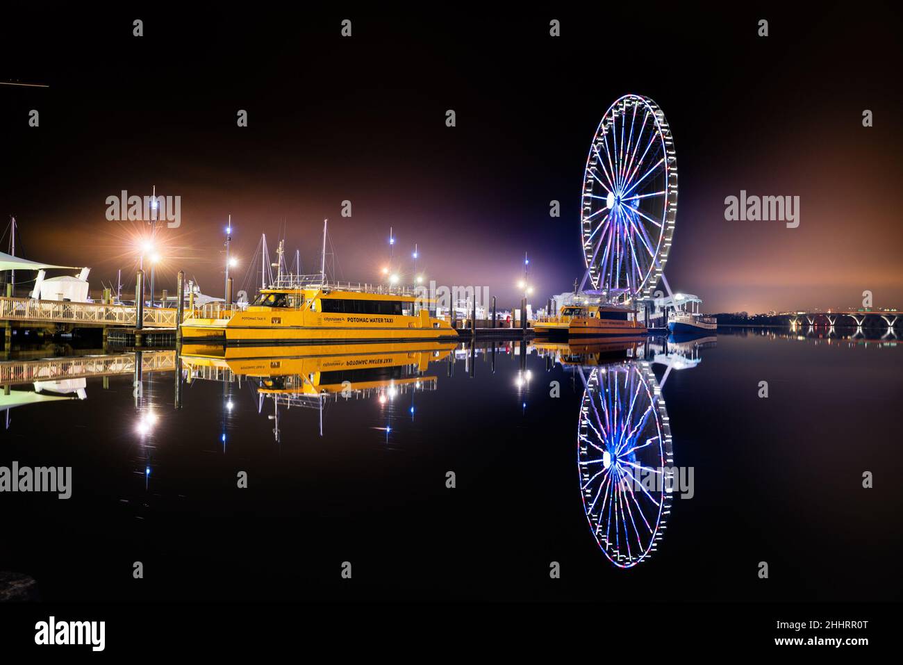 Belle scène nocturne de National Harbor Maryland au bord de l'eau avec des bateaux et la roue de ferris Banque D'Images