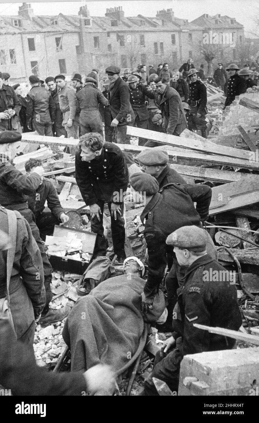 Les victimes reçoivent des premiers soins tandis que les secouristes poursuivent leur recherche parmi les décombres à la suite d'une attaque à la bombe à roquette de l'ennemi en V2 à l'usine Lead Paint de Downham Road, dans le nord de Londres.8th janvier 1945, Banque D'Images