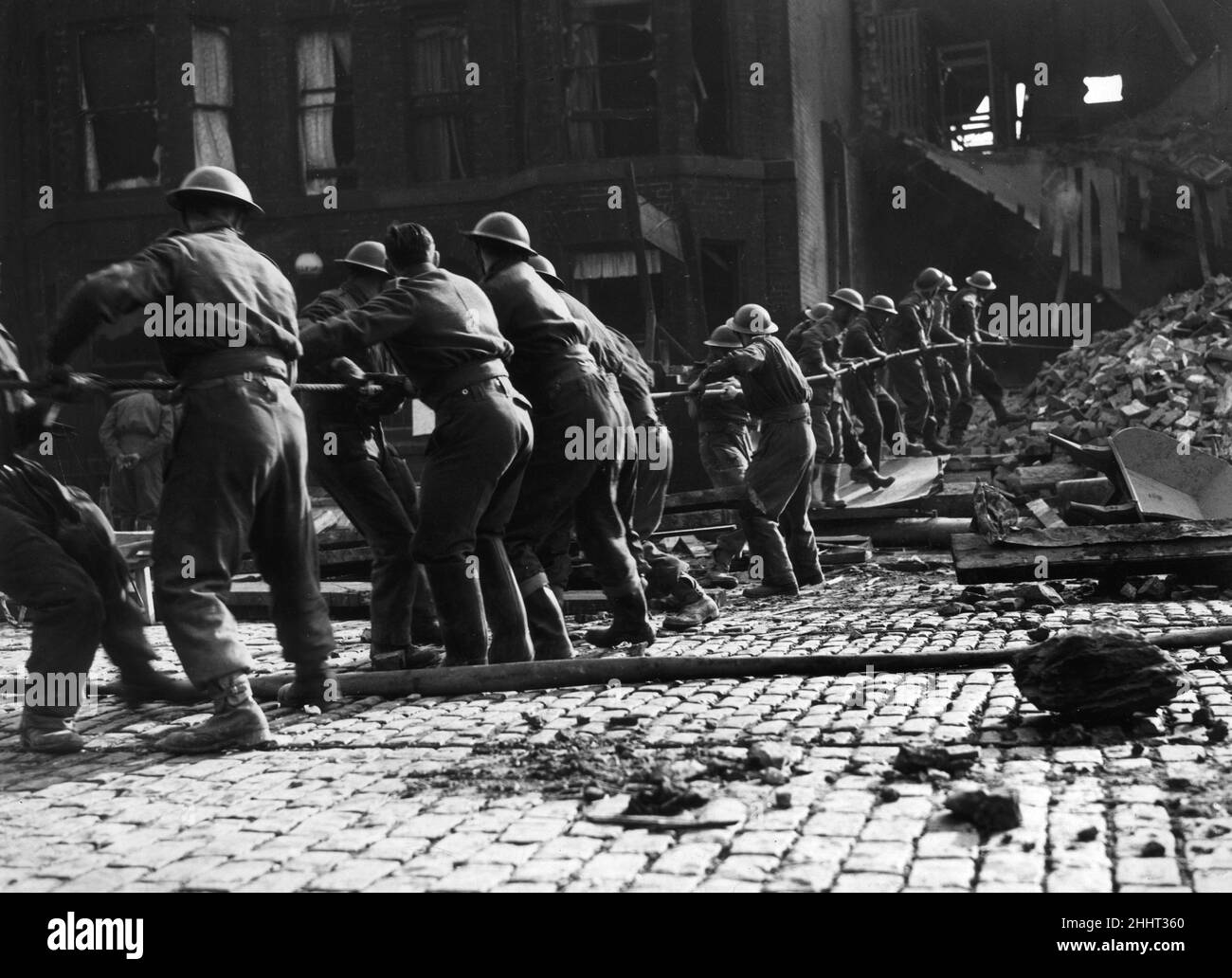 Les soldats du 8th Manchester Regiment à Ardwick Green travaillent ensemble pour éliminer les débris de leurs casernes et pour libérer leurs camarades piégés après un raid aérien allemand.Les photos montrent un groupe de soldats tirant sur la corde pour dégager l'épave.14th mars 1941. Banque D'Images