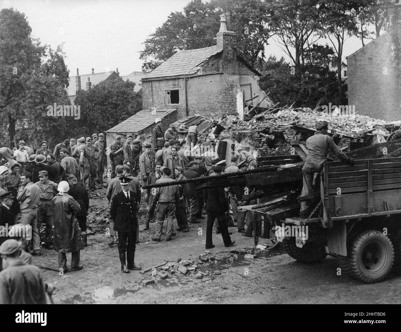 Freckleton Air Disaster 23rd août 1944American des aviateurs et des villageois recherchent des survivants après qu'un Libérateur USAAF B24 s'est écrasé dans le centre du village de Freckleton, Lancashire, Angleterre.L'avion s'est écrasé dans la Holy Trinity Church of England School, démolissant trois maisons et le Sad Sack snack bar.Le nombre de morts était de 61, dont 38 enfants.26th août 1944 Banque D'Images