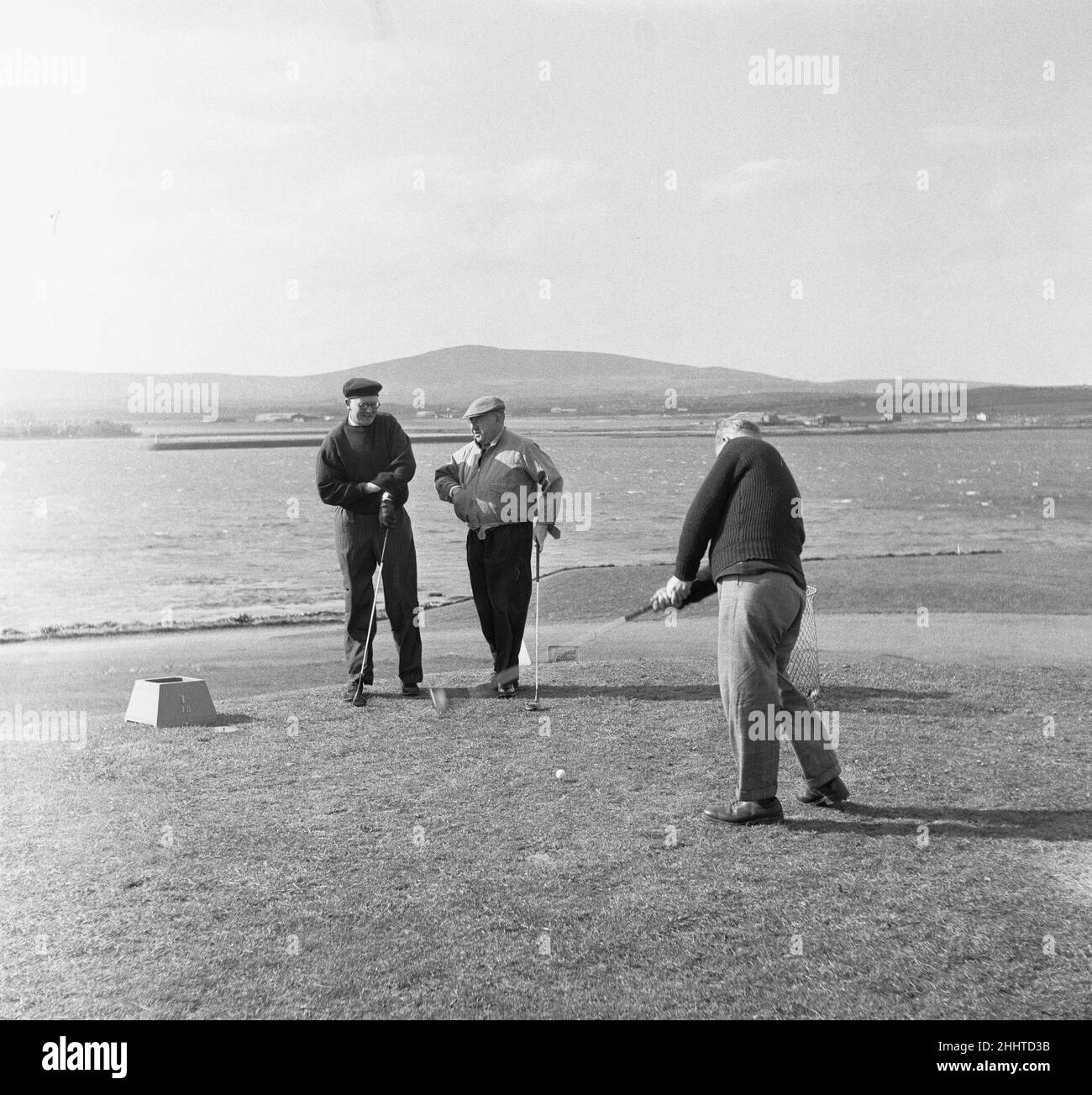 Trois amis ont fait une partie de golf sur un fort Island Golf Links Hotel très venteux sur le parcours de l'île de Man 7th mai 1954 Banque D'Images