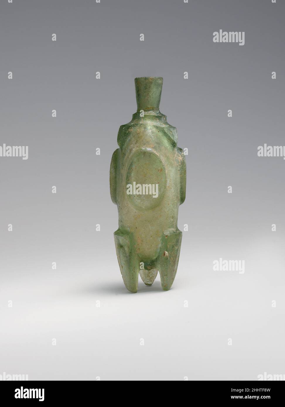 Fiole « Molar » 8th–9th siècle cette bouteille a été découpée en roue à partir d'un bloc rectangulaire de verre, puis un mince canal a été percé au milieu, rempli de kohl ou d'huile parfumée.L'objet est appelé une fiole molaire parce que ses pieds ressemblent aux racines des dents molaires.Flacon « Molar ».8th–9th siècle.Verre, vert; moulé ou soufflé, coupé.Attribué probablement à l'Iran.Verre Banque D'Images
