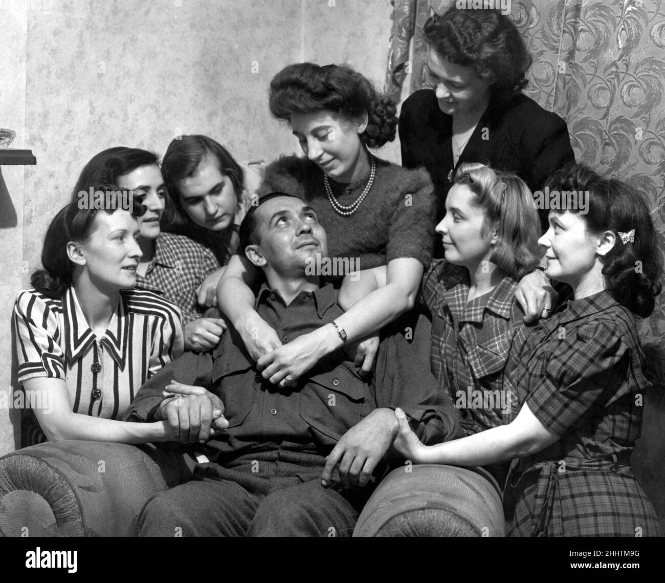 Le Soldat Albert Laws, soldat de l'armée britannique et ancien prisonnier de guerre, est rencontré par sept filles à son domicile.Son fiancé est vu avec ses bras autour de lui.8th octobre 1945. Banque D'Images