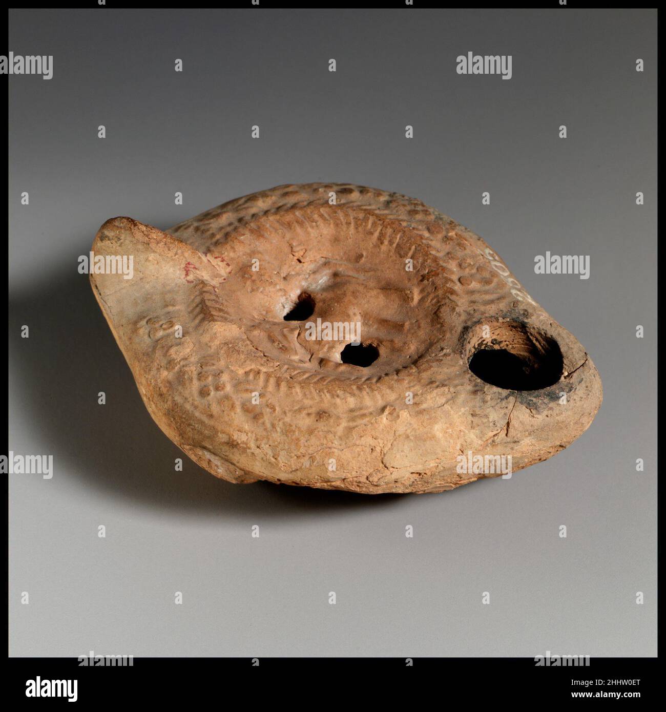 Lampe à huile en terre cuite 4th–5th Century A.D. Roman Vessberg Type 18.Poignée non percée.Moulé.Discus: Cheval traîne à gauche, avec un objet incertain suspendu au-dessus de son dos.Deux trous de remplissage.Couronne d'os de hareng autour du discus.Motif de points sur l'épaule.Grand trou de mèche.Base légèrement inégale.grosses copeaux et fissures de chaque côté du corps et autour de la buse le long de l'assemblage du moule.Lampe à l'huile en terre cuite.Romain.4th–5th siècle A.D..Terre cuite.Impérial tardif.Terracottas Banque D'Images