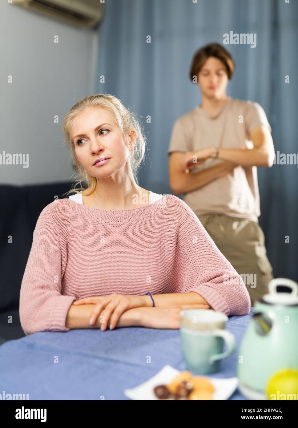 Femme contrariée assise à la table dans la cuisine Banque D'Images