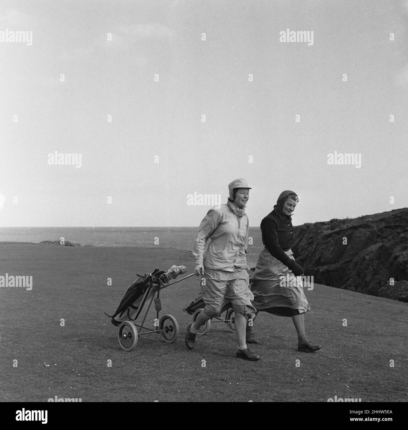 Les femmes jouant une partie de golf sur un fort Island Golf Links Hotel très venteux sur le parcours de l'île de Man 7th mai 1954 Banque D'Images