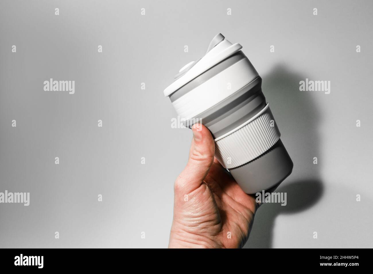 Tasse en silicone réutilisable pour café à la main sur fond blanc. Banque D'Images