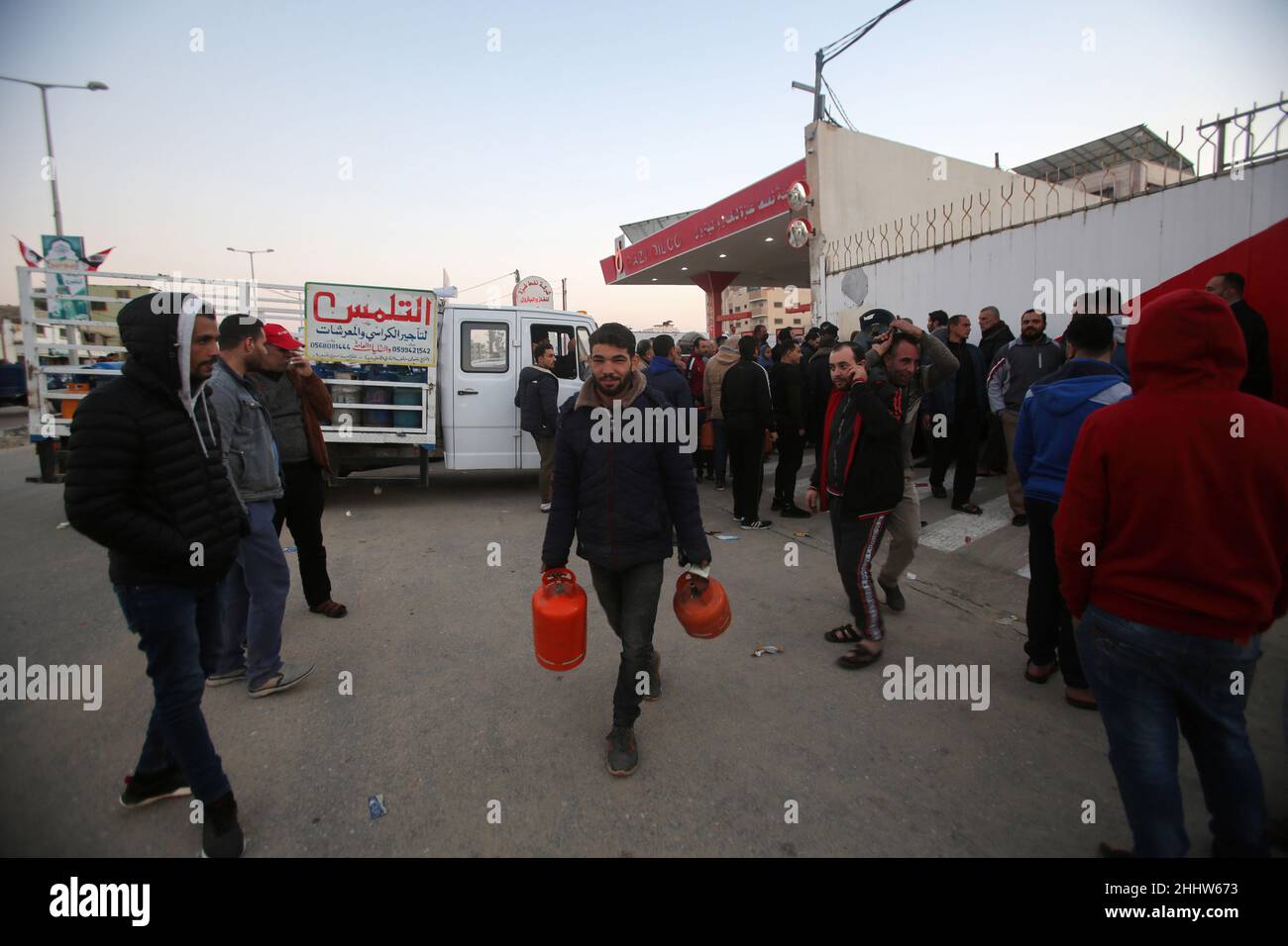 Un palestinien a vu porter des bouteilles tout en souriant après qu'il ait rempli ses bouteilles de gaz devant la grande station de gaz.Manque de gaz et incapacité à remplir les bouteilles de gaz dans leurs maisons, ce qui rend l'hiver difficile, car le gaz est une des sources de chauffage.La crise se répète presque chaque année à cette époque en raison du besoin croissant de gaz, en plus de l'absence d'une réserve stratégique de gaz pour les propriétaires des stations,La bande de Gaza obtient du gaz soit par le passage de Rafah depuis l'Égypte, soit par le côté israélien. Banque D'Images