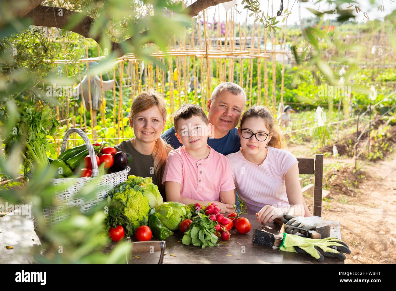 Les parents avec leurs enfants se détendent à table rustique après avoir récolté des légumes Banque D'Images
