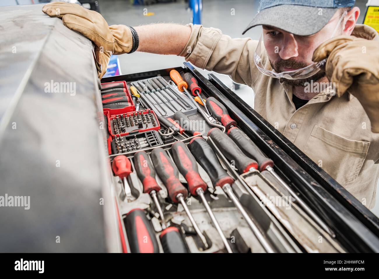 Technicien automobile à la recherche des outils adaptés à l'entretien d'une voiture.Thème de réparation de véhicule. Banque D'Images