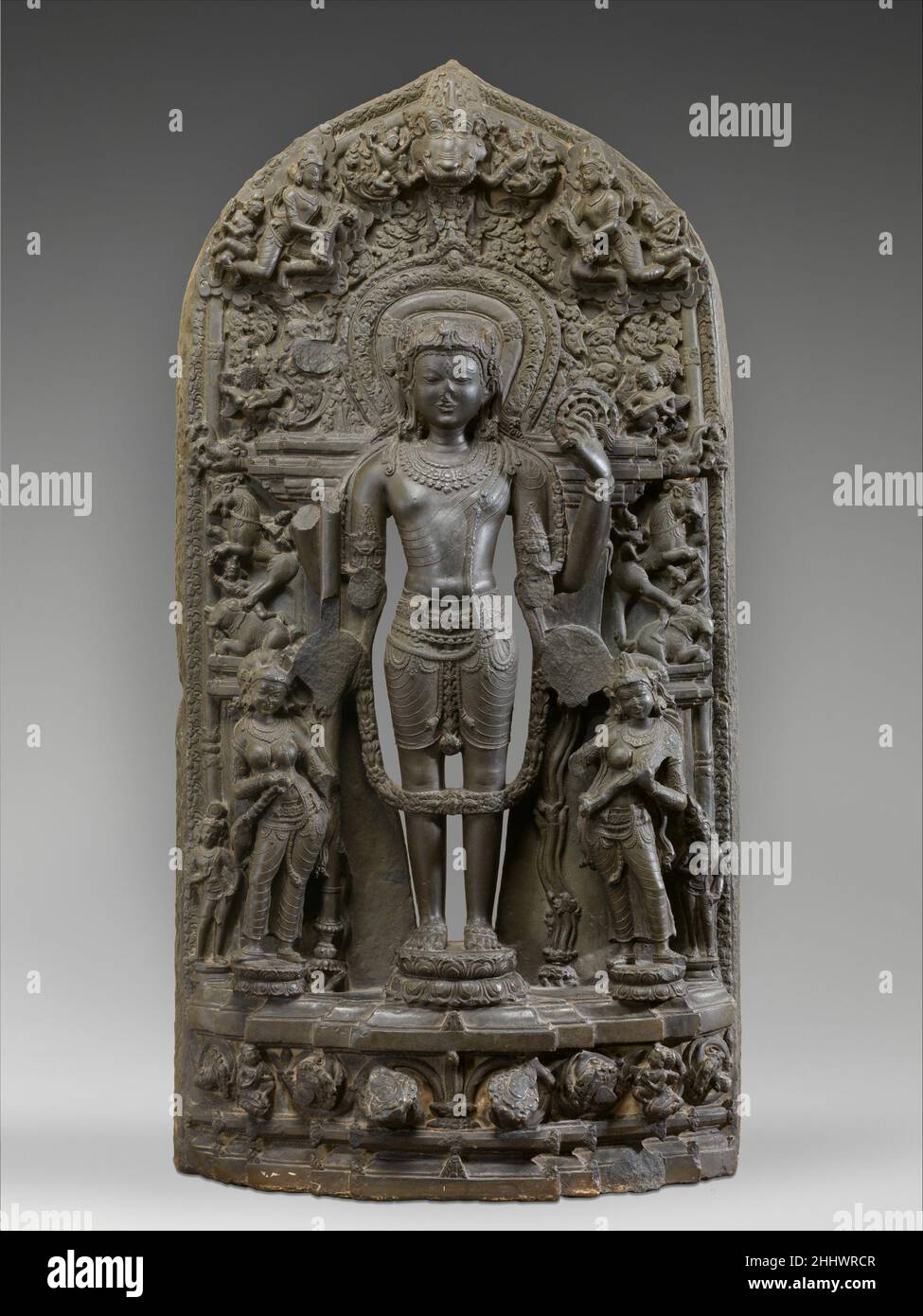 Vishnu accompagné de Lakshmi et Sarasvati 12th siècle Bangladesh Vishnu est en parfaite symétrie (samapada), le protecteur de l'ordre cosmique.Dans une convention iconographique unique au Bengale médiéval, il est accompagné par les déesses Lakshmi, tenant un fouet (camara) et lotus (padma), et Sarasvati, jouant un vina, plutôt que par ses épouses Sri Devi et BHU Devi.Il est aussi étroitement associé à Priti, la déesse de la terre, qui apparaît souvent entre ses pieds.Les déesses sont à leur tour flanquées de deux figures miniatures, les personnages mâles des armes de Vishnu, le conch (sankha) et Banque D'Images