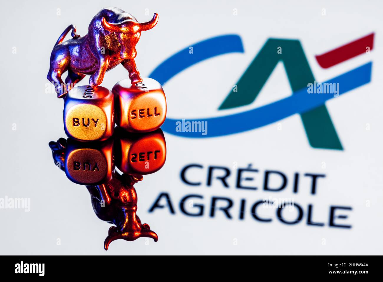 Le taureau métallique se dresse sur des dés d'achat-vente sur le fond du logo de la banque crédit agricole Banque D'Images