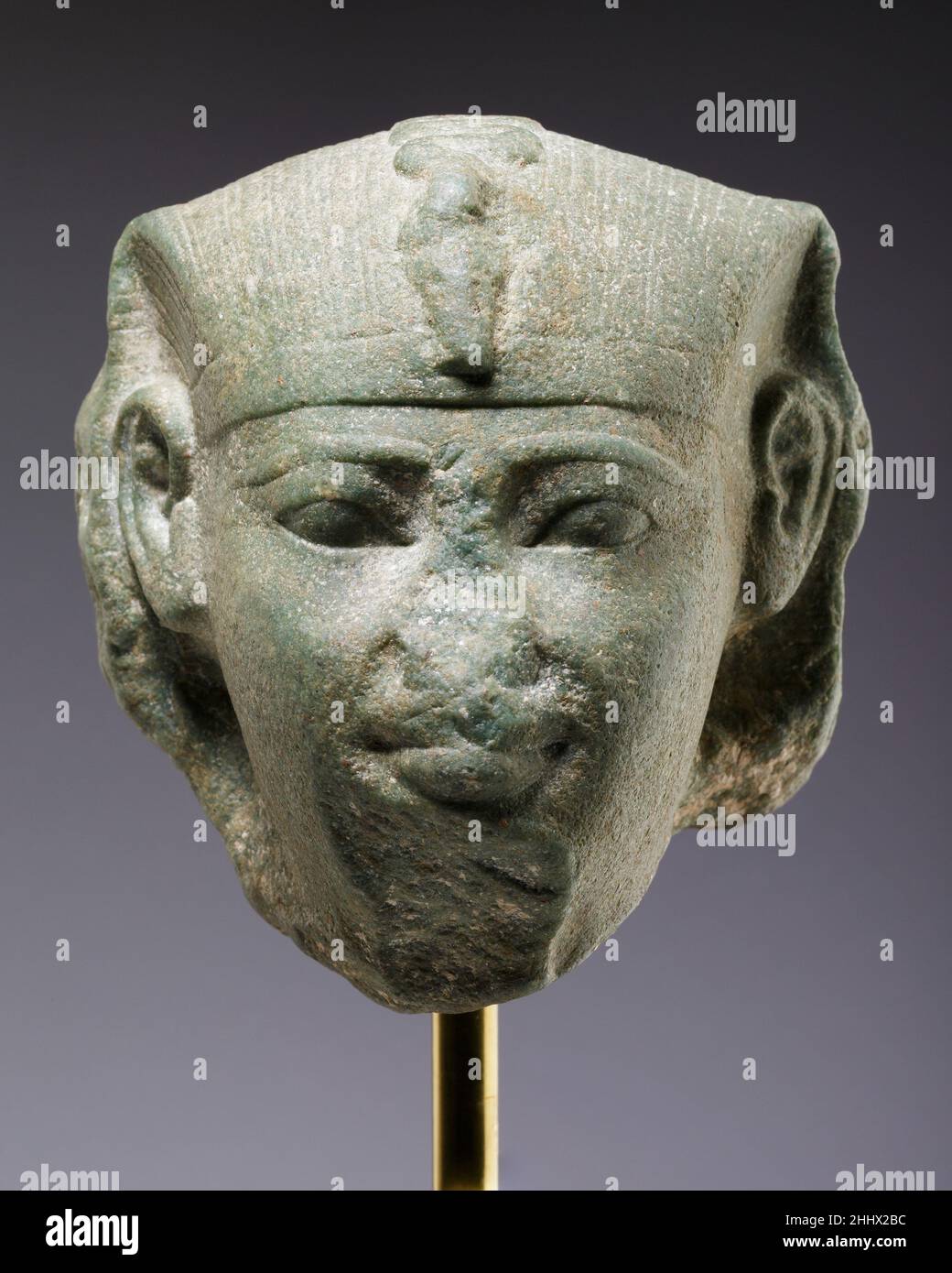 Chef d'un sphinx, peut-être d'Amenemhat je ca.1981–1952 B.C. Middle Kingdom la bouche souriante, les yeux larges ouverts et les joues arrondies suggèrent un roi jeune, et les proportions des nemes, ainsi que la profondeur de la rupture, indiquent que la tête faisait partie d'un sphinx comparativement petit.Le front bas, les sourcils hauts et la position élevée des oreilles rappellent la tête du Metropolitan Museum of Art attribuée à Mentuhotep III (66.99.3), mais les yeux de la tête actuelle sont plus grands, les joues plus maigres et la bouche plus modulée.Ces caractéristiques sont également vues dans la tête d'une statue i Banque D'Images