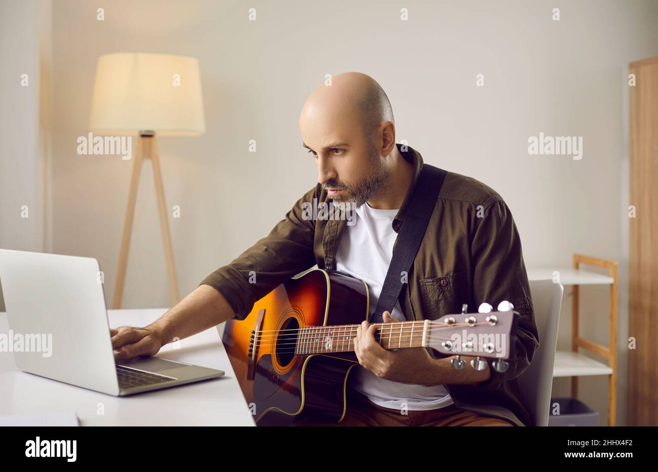 Musicien apprenant à jouer de la guitare à la maison et regardant des didacticiels vidéo sur ordinateur portable Banque D'Images