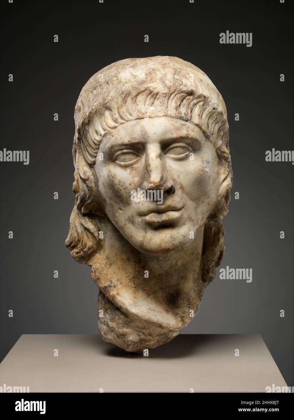 Tête en marbre d'un homme A.D. 69–96 Roman les vagues de cheveux plates disposées avec soin autour du visage et les longs cheveux en vrac à l'arrière indiquent que cet homme a tenu une certaine position dans la rétine impériale.Certaines figures représentées dans les processions triomphales sculptées sur l'Arche de Titus à Rome et sur l'Arche de Trajan à Beneventum sont montrées avec de longs cheveux.Ils portent des panneaux peints, des boucliers ou des candélabres.Bien que leur fonction ou bureau exact soit inconnu, les cheveux longs doivent avoir été un trait distinctif important.Tête en marbre d'un homme 248801 Banque D'Images