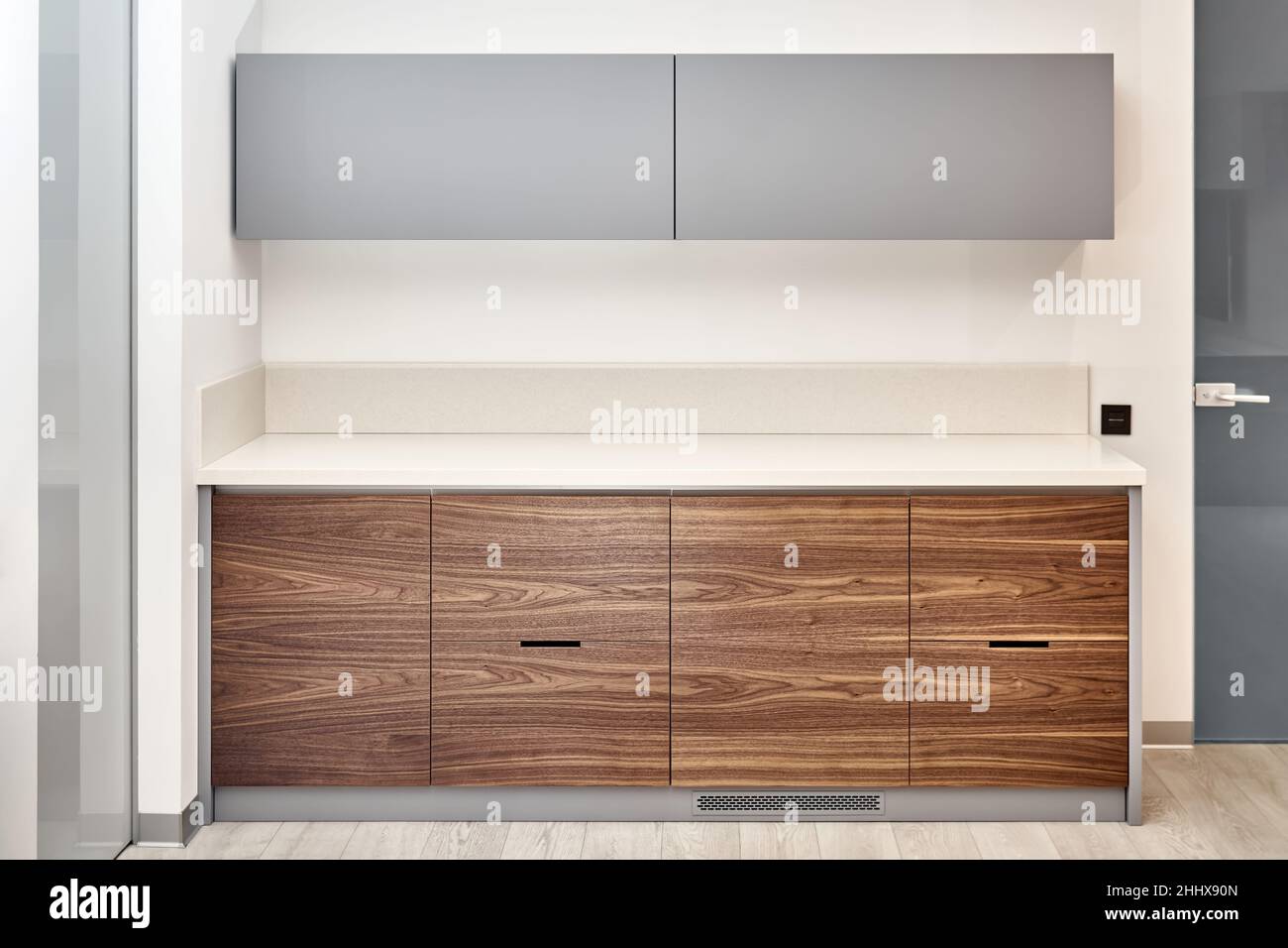 Mobilier de cuisine contemporain de style minimaliste en bois de noyer et de couleur grise, comptoir en acrylique à surface solide dans le bureau Banque D'Images