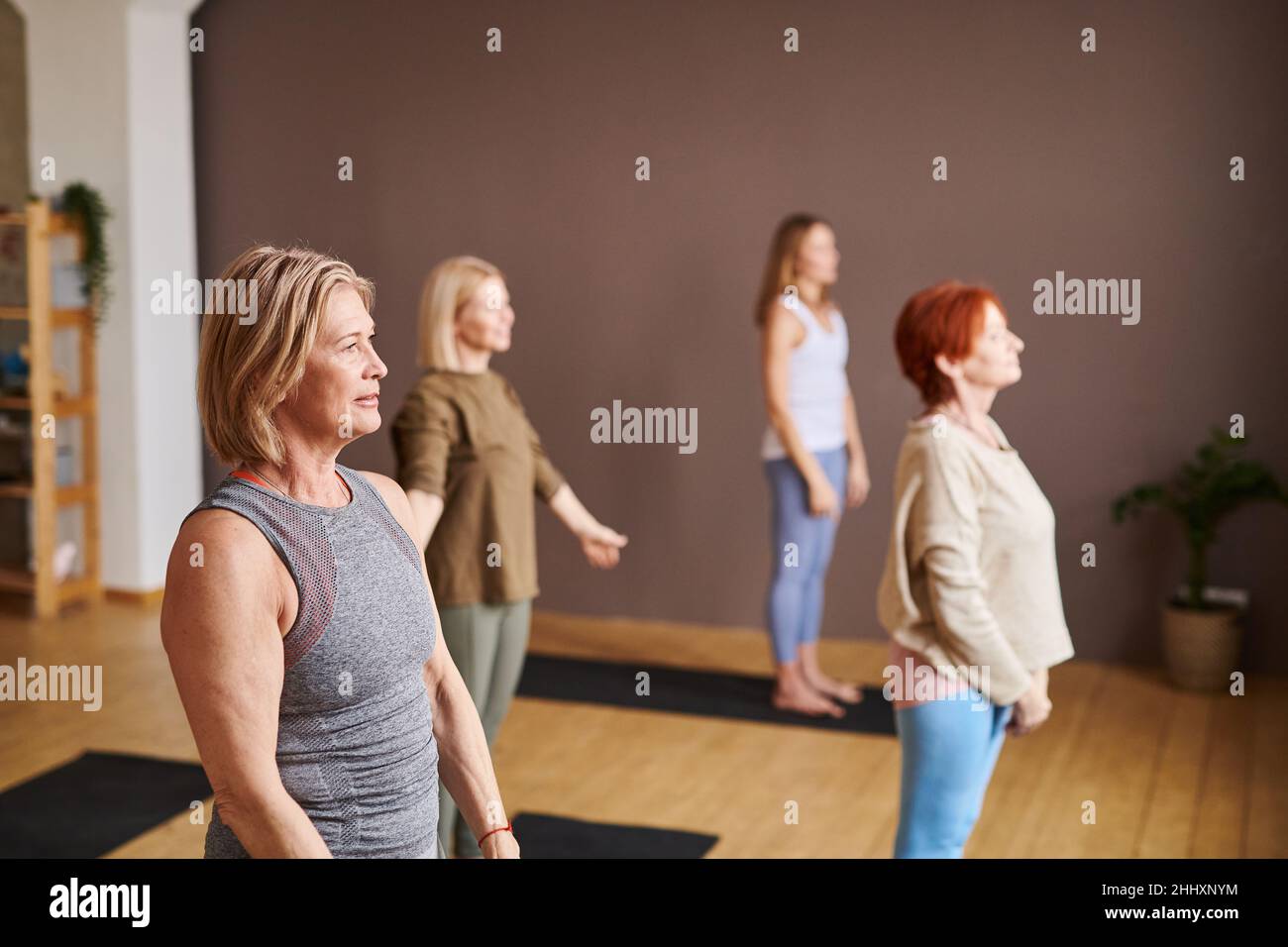 Groupe de femmes en vêtements d'activité debout sur des tapis et faisant des exercices de relaxation pendant l'entraînement dans la salle de gym ou le centre de fitness Banque D'Images