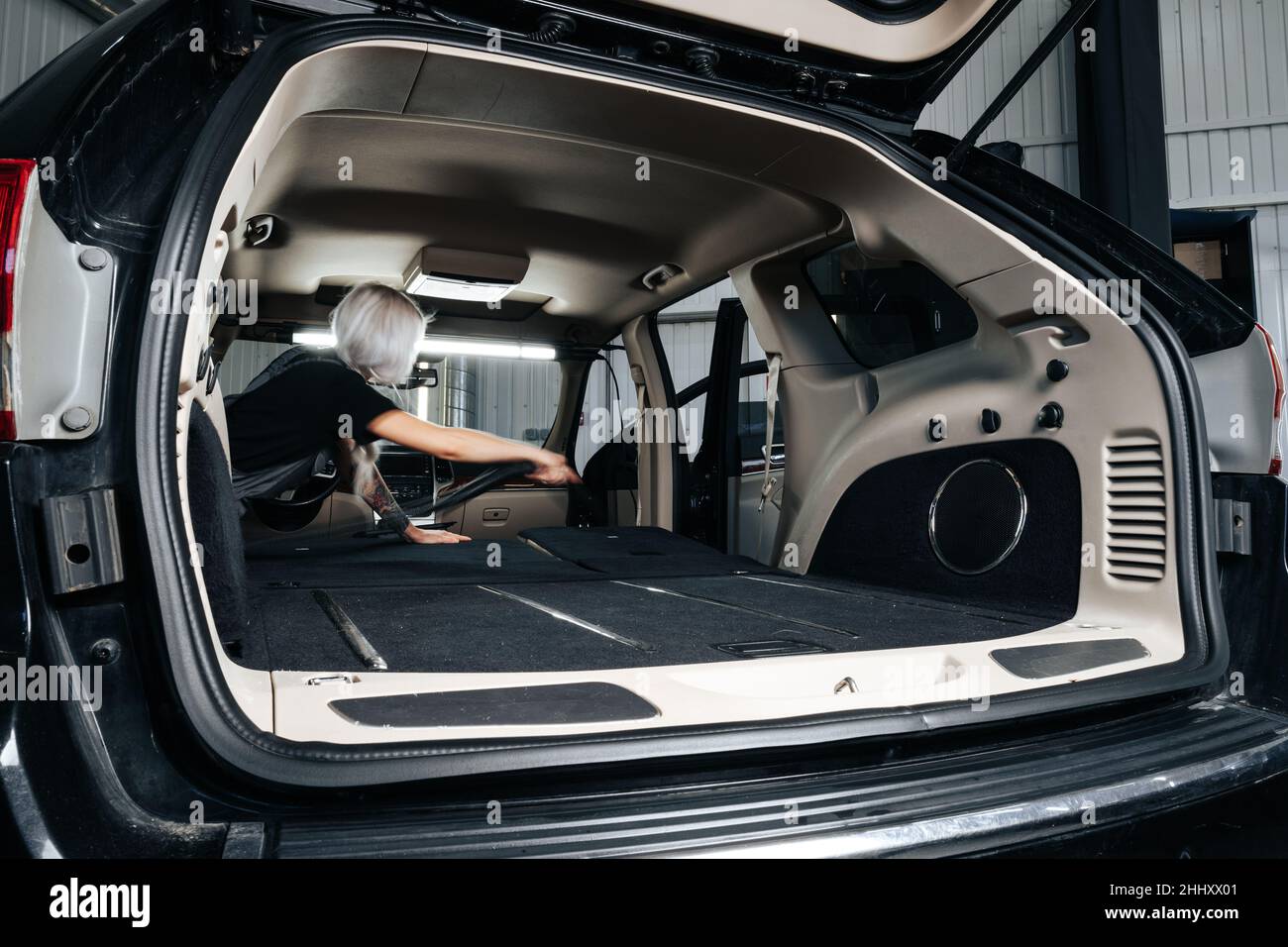 Femme travailleuse aspirant poussière intérieur de la voiture dans le lave-auto. Banque D'Images