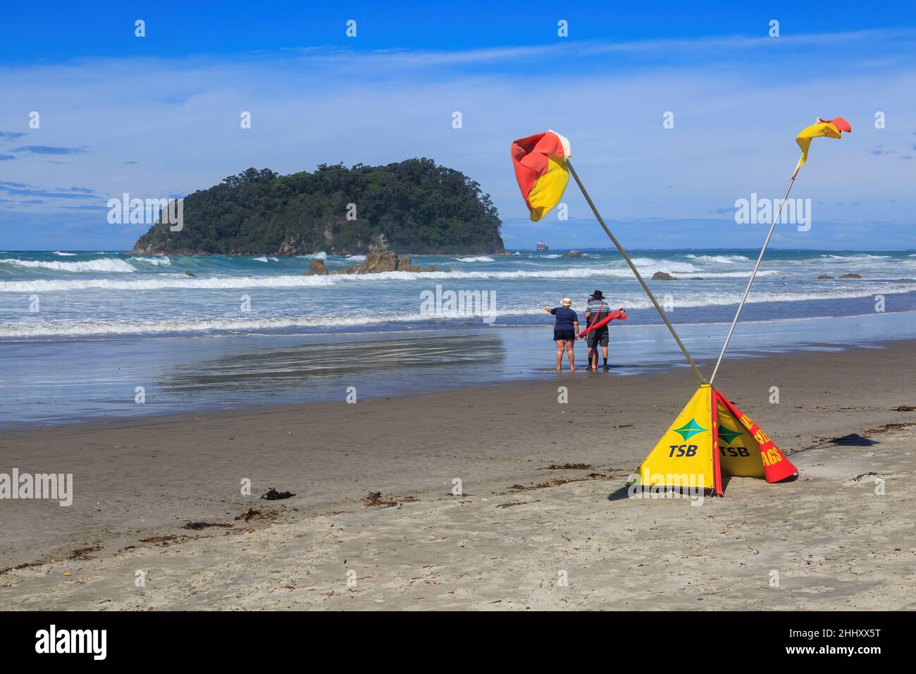 La plage du mont Maunganui, en Nouvelle-Zélande, avec des drapeaux de surf croisés pour prévenir les gens de ne pas nager dans les eaux rugueuses Banque D'Images