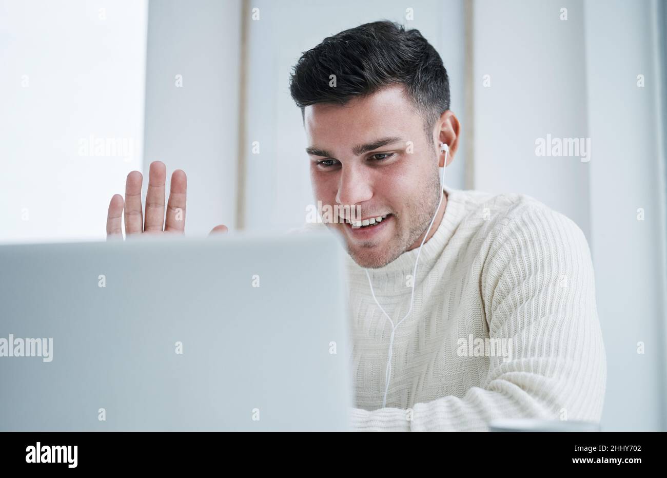 J'espère que tout le monde se porte bien.Photo d'un jeune homme utilisant un ordinateur portable pour passer un appel vidéo tout en travaillant à domicile. Banque D'Images