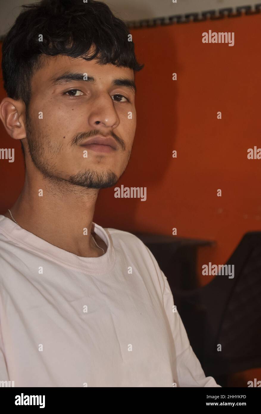 Gros plan d'un jeune garçon indien charmant assis à l'intérieur avec regarder la caméra Banque D'Images