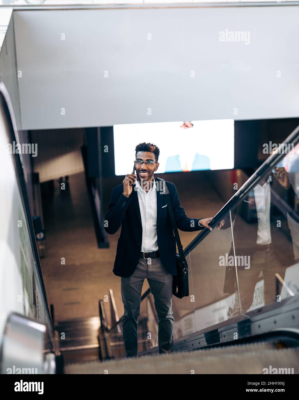 Souriant jeune homme d'affaires noir utilisant son smartphone tout en sortant du métro Banque D'Images