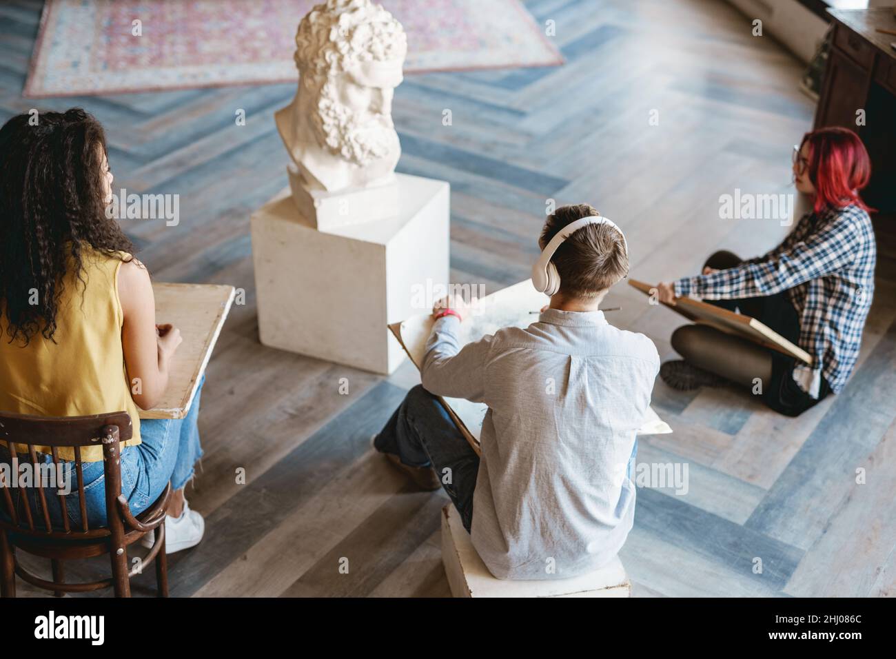 Jeunes élèves blancs qui dessinant un buste en plâtre pendant la classe à l'école d'art à l'intérieur Banque D'Images