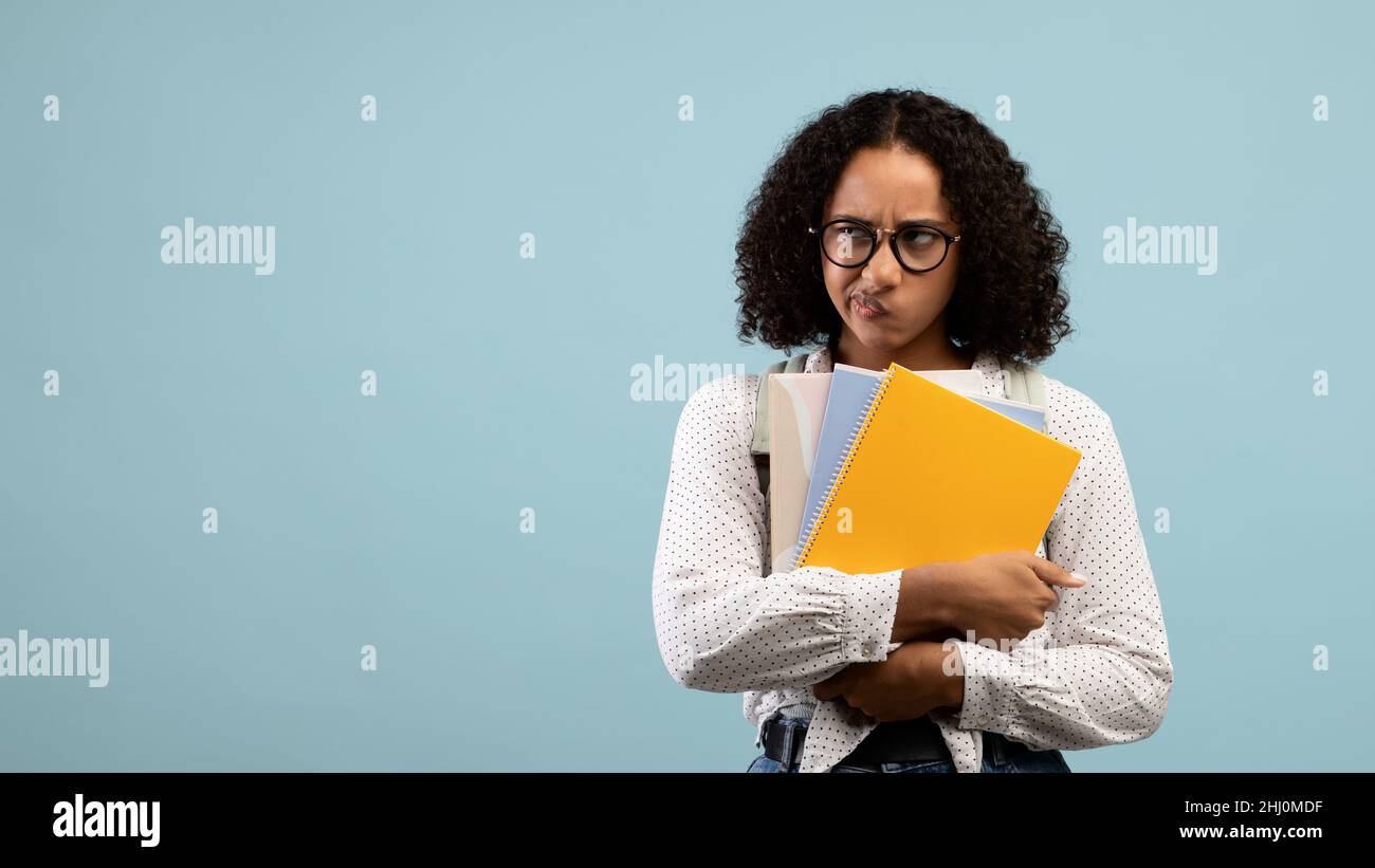 Femme noire frustrée étudiant avec sac à dos et ordinateurs portables regardant l'espace vide, se sentant stressé sur fond bleu Banque D'Images