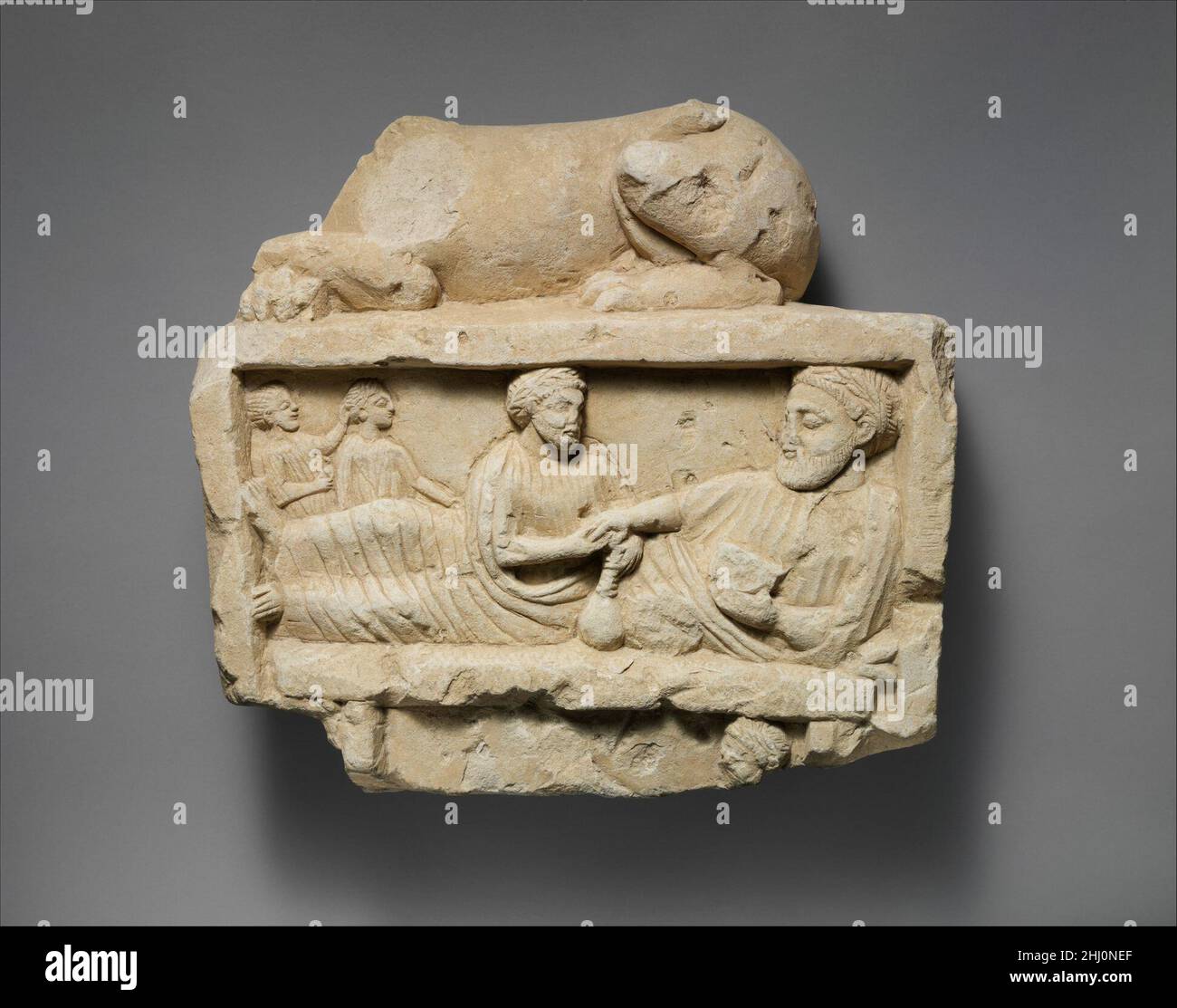 Finale en calcaire d'une stèle funéraire avec un lion allongé et une scène de banquet 5th–4th siècle au-dessus du lion chypriote de Colombie-Britannique; banquet avec deux hommes et deux enfants.Finale calcaire d'une stèle funéraire avec un lion allongé et une scène de banquet 242395 Banque D'Images