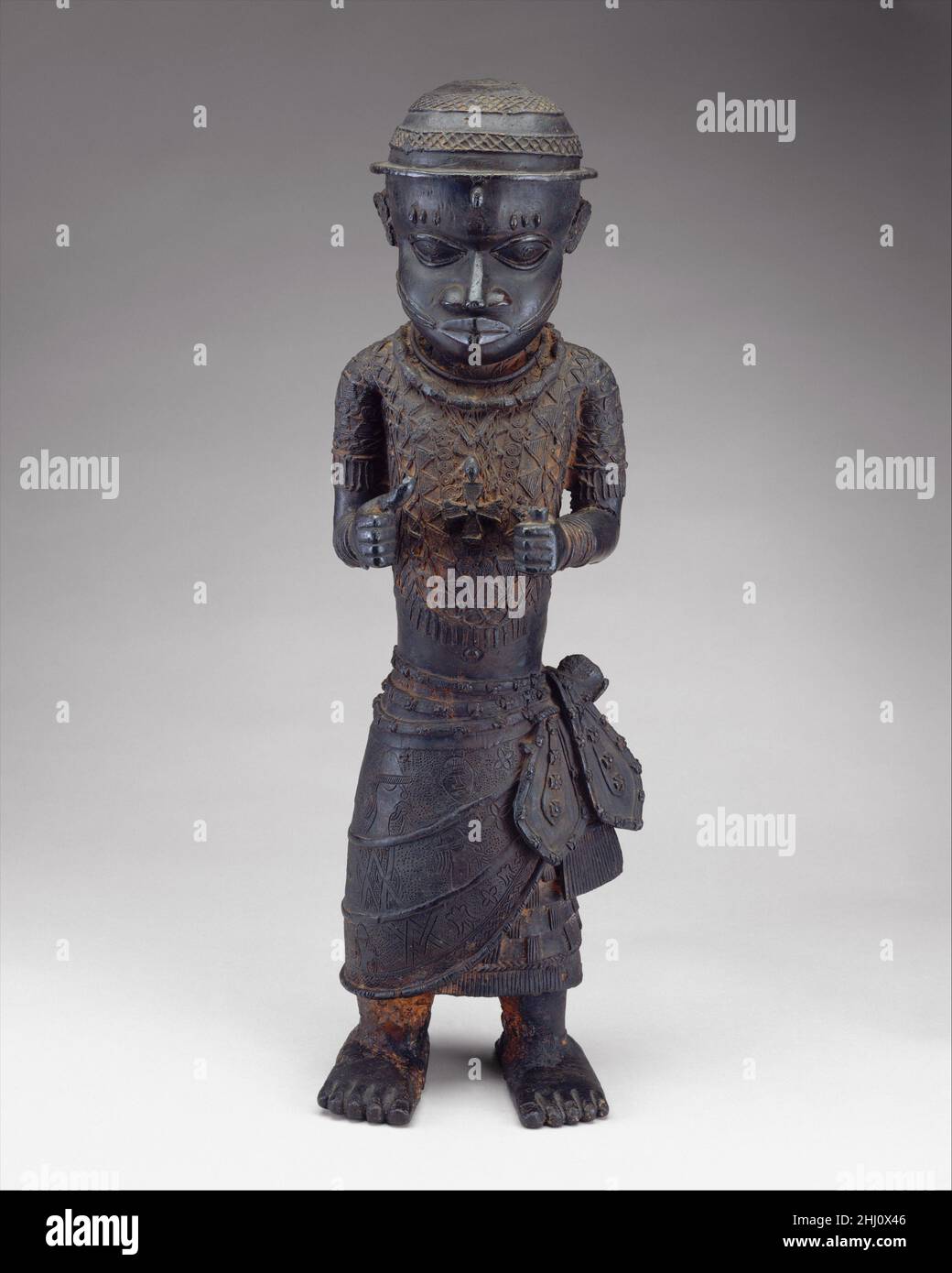 Figure masculine: Officiel de la Cour 16th–17th siècles peuples Edo les boursiers ont suggéré que cette figure a été placée sur un autel commémoratif dédié à un roi, ou 'oba,' du Bénin.La figure est représentée avec une suspension en croix distinctive.Sa jupe enveloppante est ornée de têtes de profil de commerçants portugais, d'une tête frontale africaine, et d'autres motifs béninois communs tels que les feuilles de rivière, le mudfish, et les motifs entrelacés.trois identités différentes ont été proposées pour ce chiffre.Le fonctionnaire peut être un messager d'un dirigeant appelé 'Ogane,' qui est aujourd'hui identifié comme le chef, ou 'oni,' o Banque D'Images