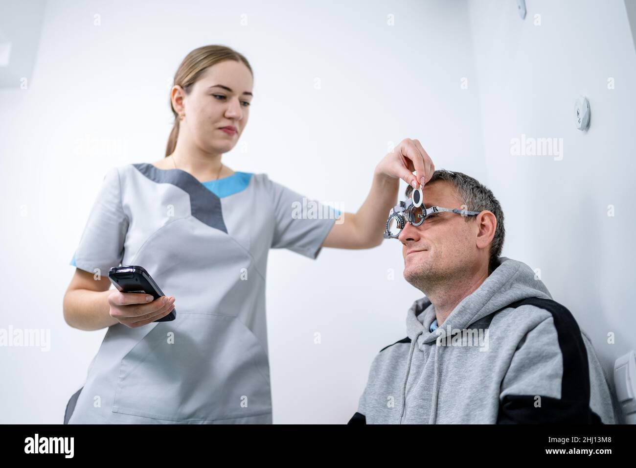 Le patient masculin subit un test oculaire et une prescription de lunettes en clinique d'ophtalmologie.Optométriste vérifiant la vue et la vision du patient Banque D'Images