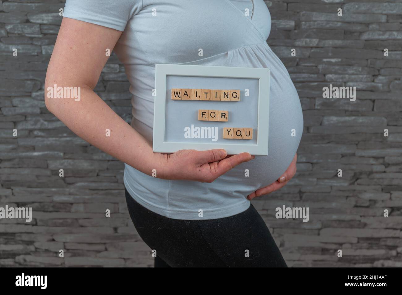 La femme enceinte en 30s tient le signe devant son ventre enceinte Banque D'Images