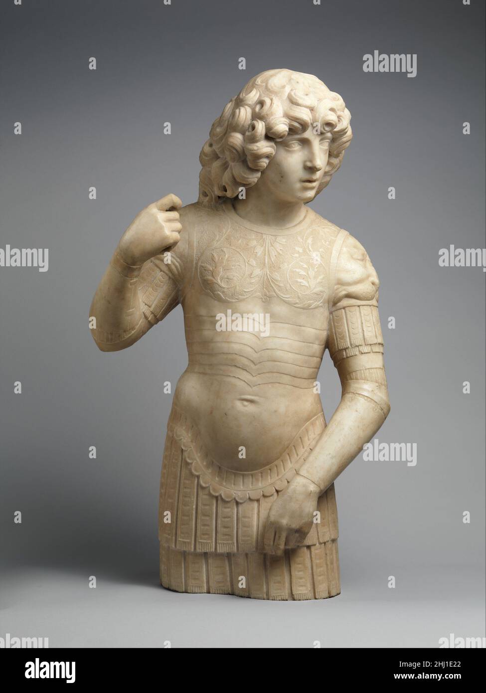 Un jeune guerrier 1490s Tullio Lombardo cette jeunesse revêtue d'armure de style ancien peut représenter Saint George ou Saint Theodore, des guerriers chrétiens qui ont été particulièrement vénérés à Venise.Il aurait mené une lance dans sa main droite et aurait peut-être gardé un tombeau.Sa posture énergique, sa torsion de la tête et ses bras tensément tenus transmettent la vigilance requise d'une figure de gardien.La véracité aux exemples classiques a été estimée dans la Renaissance Venise; ce sculpteur a accordé une attention particulière à rendre les vignes à défilement délicatement texturées qui décorent le pectoral, et même sculpté les lacets qui tiennent Banque D'Images