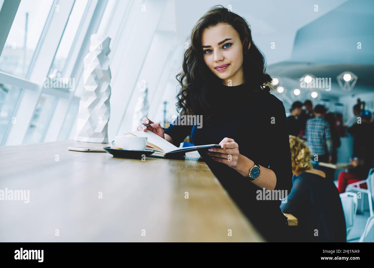 Femme souriante avec un carnet et une tasse de café Banque D'Images