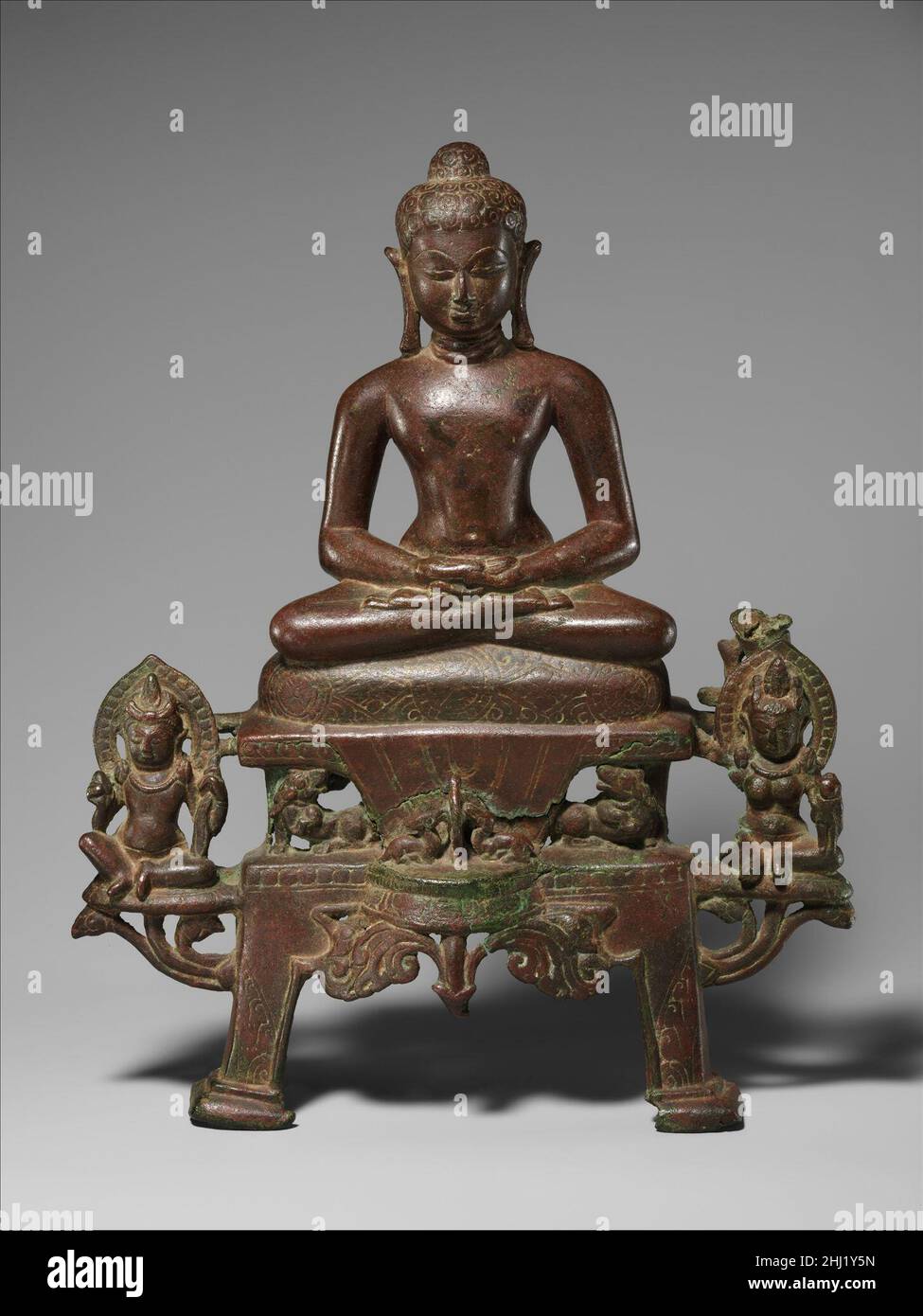 Enthroned Jina, probablement Neminatha fin du 7th siècle Inde (Gujarat, Akota) un savior Enthroned Jain est profondément dans la méditation, assis dans une posture yogique sur un coussin orné de bijoux sur un trône à deux niveaux soutenu par des lions.Au centre du piédestal, deux cerfs à genoux vénérèrent la roue de la loi (dharmachakra), symbole de la sagesse religieuse partagée avec le bouddhisme.Assis à l'aise royale sur la projection des supports de lotus sont les yaksha Gomedha et les yakshi Ambika, les serviteurs de la jina Neminatha, la vingt-deuxième dans la lignée de vingt-quatre jinas historiques reconnues par la religion de Jain.En marche arrière, la tension est de Banque D'Images