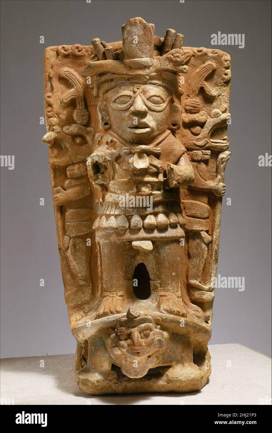 Censeur support mi-7th–9th Century Maya ce cylindre en céramique à bride modélisé à la main aurait soutenu un bol pour la combustion de l'encens à des fins rituelles.Une figure debout à relief élevé avec un motif en boucle entre ses yeux, qui est pensé pour se rapporter au dieu Maya du soleil, est représentée sur le devant.La figure est flanquée de deux plus petites figures en forme de personnel, masquées par des animaux, illustrées dans le profil.Les trois figures sont placées au sommet de la carapace d'une tortue dont le devant émerge une tête humaine, probablement une représentation d'une divinité maya underworld.Les coquilles de tortue étaient considérées comme des méta Banque D'Images