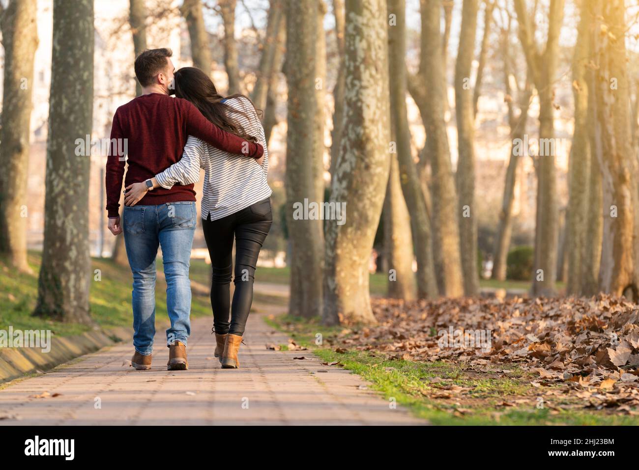 Jeune couple hétérosexuel marchant et s'embrassant dans un parc le jour de la Saint-Valentin Banque D'Images