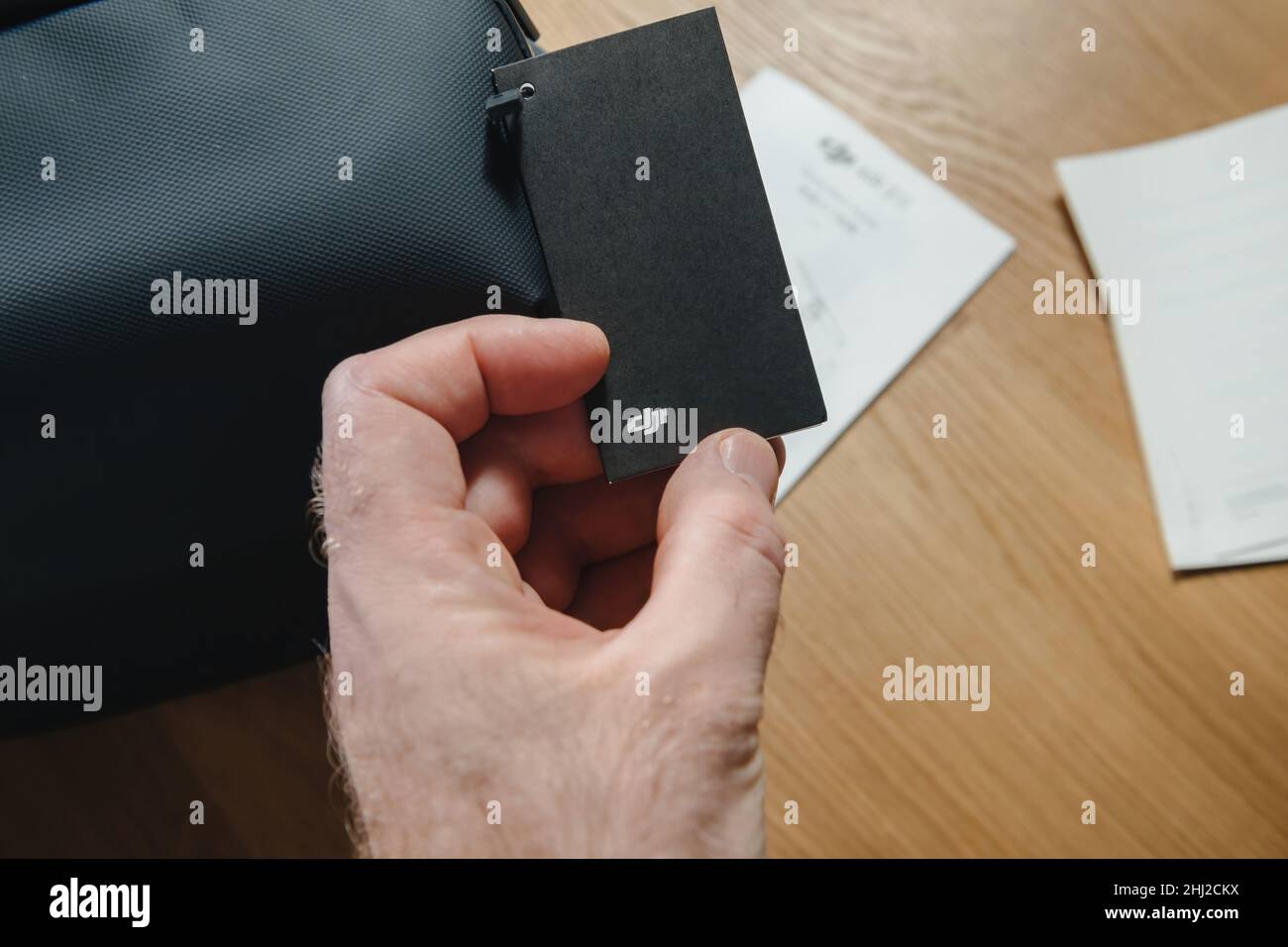 Paris, France - 14 janvier 2022: POV main mâle tenant le papier noir de luxe avec le logotype DJI après avoir déballer un nouveau drone sac à bandoulière.DJI est une société de technologie chinoise dont le siège est situé à Shenzhen, Guangdong, Banque D'Images