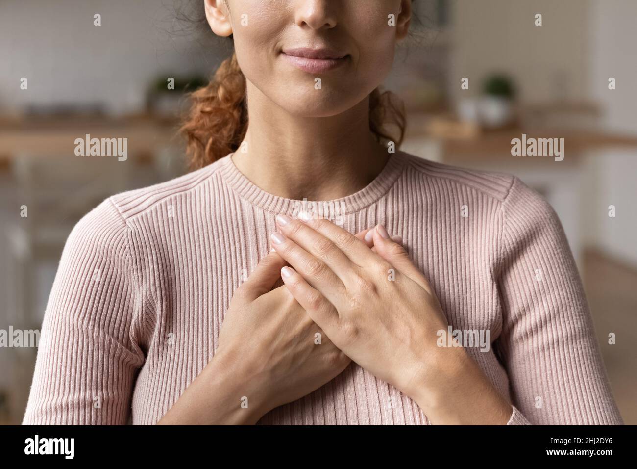 Une femme sincère a mis les paumes pliées sur la poitrine en sentant la gratitude en gros plan Banque D'Images