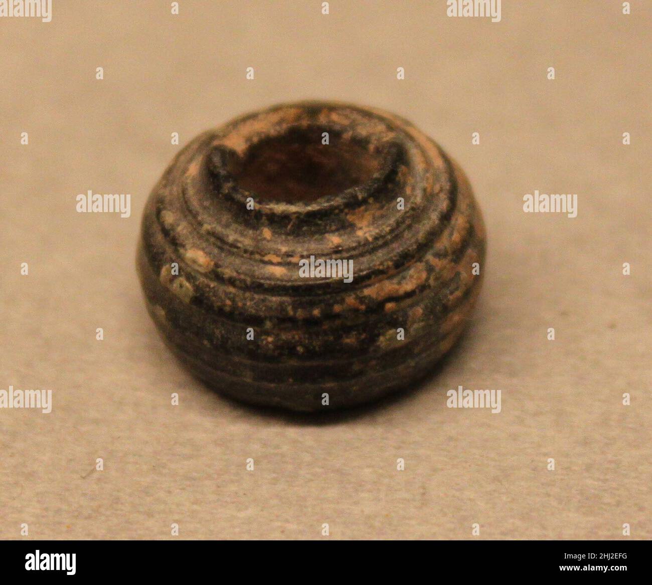 Perle 8th–13th siècle cet objet a été fouillé à Nishapur.Nishapur était une ville vitale au début et au milieu des périodes islamiques, située le long d'une des principales trajectoires qui reliaient l'Iran et les terres islamiques de l'Asie occidentale à l'Asie centrale et à la Chine.Ces itinéraires sont souvent mentionnés par le terme «itinéraires de Silk», mais ont en fait été cruciaux pour le mouvement des constellations de matériaux et d'objets, ainsi que des personnes et des idées.La population diversifiée de Nishapur et de ses environs, des groupes d'élite de marchands mieux étudiés, de l'aristocratie propriétaire de terres et des alphabétisés, à l'arti moins connu Banque D'Images