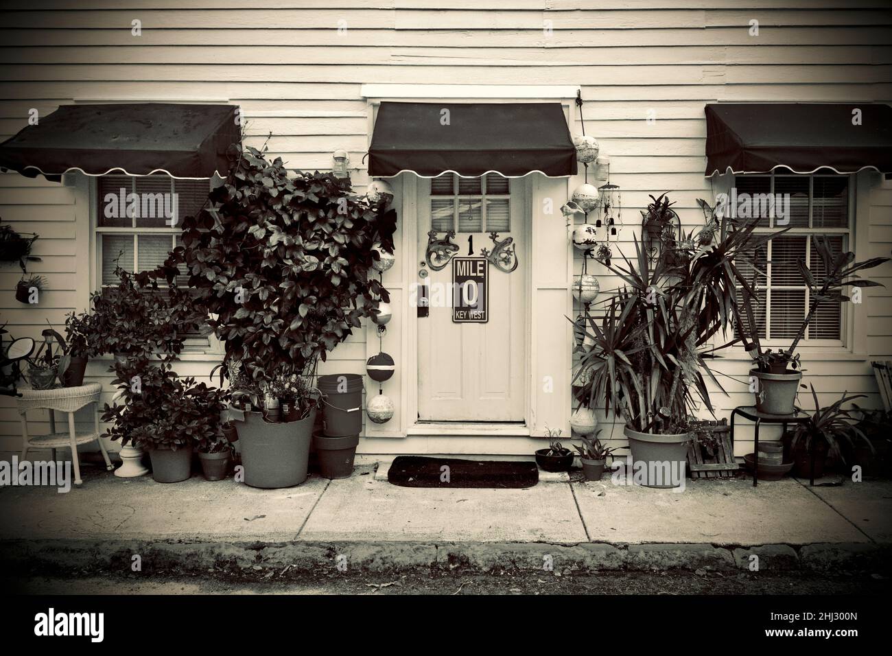 Porte avant avec marqueur de distance “0” et geckos décoratifs à Key West, Floride, FL, États-Unis.Des bouées de pêche suspendues et un auvent rouge entourent la porte. Banque D'Images