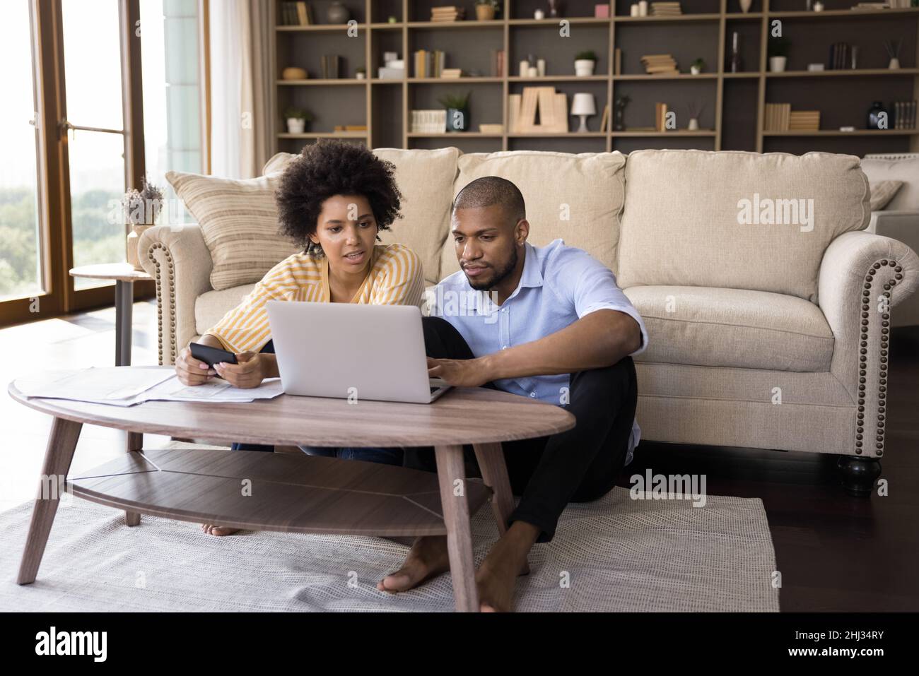 Un couple africain sérieux paie des factures en ligne, calcule les dépenses à la maison Banque D'Images